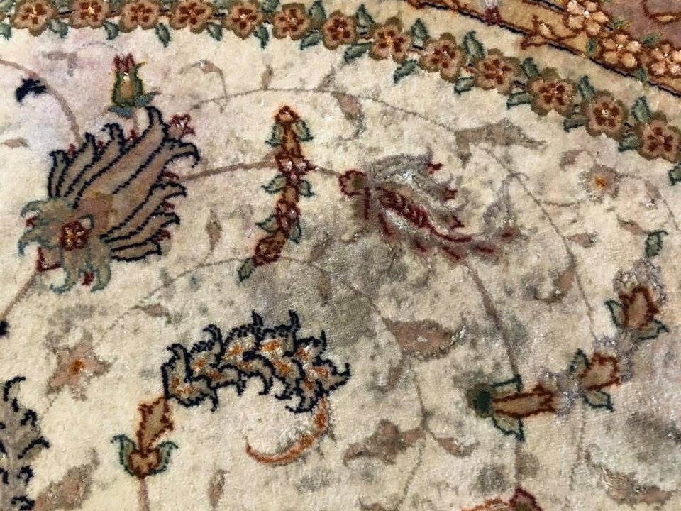 Close view of a finely knotted rug showing discoloration in the field